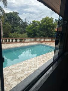 una piscina vista a través de una ventana de una casa en Chacara dos oliveiras, en São Paulo