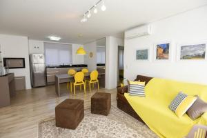sala de estar con sofá amarillo y cocina en Rosa Edifício Van Gogh, en Gramado