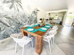 a dining room with a wooden table and white chairs at Villa Carpe Diem sea front pool Orient Bay in Orient Bay
