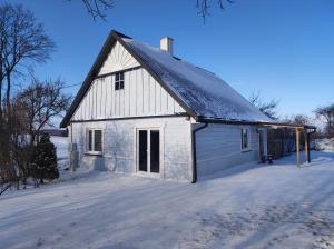 un granero blanco con techo negro en la nieve en Dom na Suwalszczyźnie, en Krasnopol