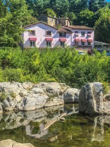 een huis op een heuvel naast een waterlichaam bij Logis Hotel Restaurant la Corniche des Cevennes in Saint-Jean-du-Gard