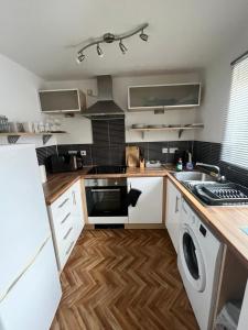 uma cozinha com armários brancos e uma máquina de lavar e secar roupa em The Onyx Suite - 1 Bed apartment w/ free parking em Cardiff