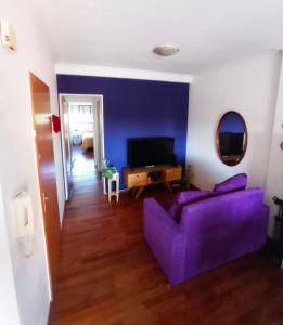 a living room with a purple couch and a tv at Alójate en Pichincha Dpto completo en el corazón de Pichincha, el barrio mas lindo de Rosario in Rosario