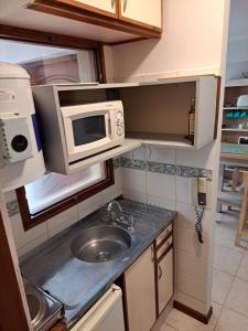 una pequeña cocina con fregadero y microondas en Leonidas apartments en Mendoza