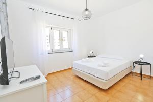 a white bedroom with a bed and a television at K - ViewPoint of Lagos GuestHouse in Lagos
