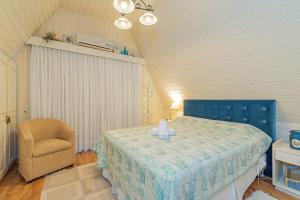 1 dormitorio con 1 cama azul y 1 silla en Rosa Casa Vale do Bosque, en Gramado