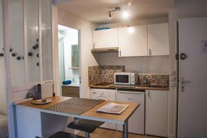 a small kitchen with a table and a microwave at Grand Studio neuf Parking Privatif 3 minutes Gare au calme in Poitiers