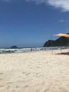 a beach with an umbrella and people in the water at Casa em Camburi in Camburi