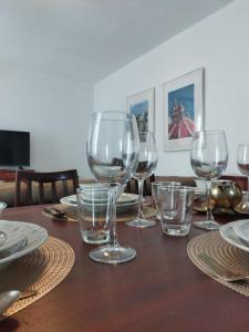 a wooden table with wine glasses and plates on it at Centrally Located Bugibba Apartment - Seaside Comfort in St Paul's Bay