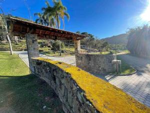 a stone wall next to a park with a bench at Casa de Campo - Hospedar com Propósito in Florianópolis