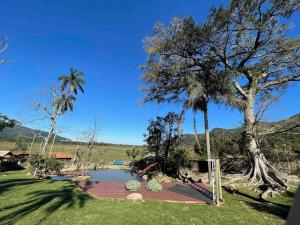 a pool in the middle of a yard with palm trees at Casa de Campo - Hospedar com Propósito in Florianópolis