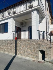 a white house with a stone wall and a balcony at TheonikosHouse in Agros