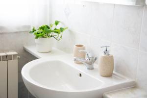 a white sink in a bathroom with a potted plant at CA' GIALLA 2 - sul Lago di Lugano, self check-in e parcheggio - in Cadegliano Viconago