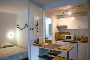 una pequeña cocina con escritorio y una cama en una habitación en Grand Studio neuf Parking Privatif 3 minutes Gare au calme, en Poitiers