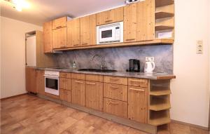 La cuisine est équipée de placards en bois, d'un évier et d'un four micro-ondes. dans l'établissement 3 Bedroom Cozy Apartment In Vodernberg, à Vordernberg