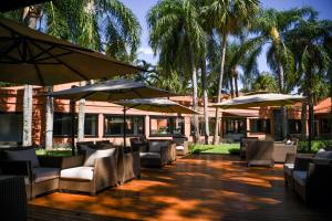 a patio with chairs and umbrellas and palm trees at Sanma Hotel in Foz do Iguaçu