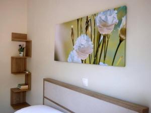 a painting of flowers on the wall of a bedroom at Agios Leon Apartment 2 in Agios Leon
