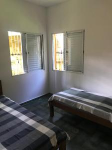 two beds in a room with two windows at Casa em Camburi in Camburi