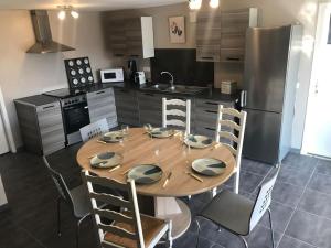 kuchnia z drewnianym stołem z krzesłami i lodówką w obiekcie Maison avec piscine au calme w mieście Puygiron