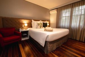 a bedroom with a large bed and a red chair at Sanma Hotel in Foz do Iguaçu
