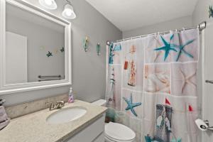 a bathroom with a shower curtain with a toilet and a sink at Beach Haven - Seasonal Hot Tub, Fire Pit, BBQ, 700 Feet to Beach, Central PCB, FREE Daily Activities, & More! in Panama City Beach +40 photos