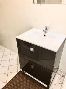 baño con lavabo blanco y armario negro en Studio Apartment near to Paris, en Créteil