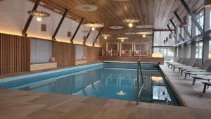 a swimming pool in a large room with chairs and tables at Hotel Zebru in Solda