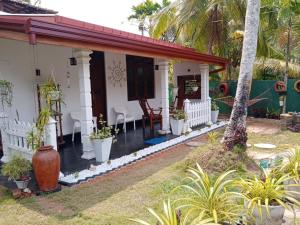 uma casa branca com um alpendre com plantas em Friendly home stay em Etagama