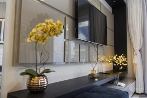 - un salon avec un vase orné de fleurs jaunes sur une table dans l'établissement Rosa Edifício Centro One, à Gramado 56 autres photos