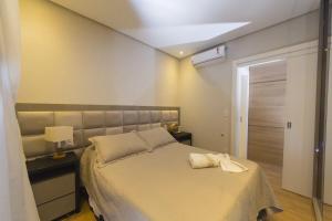 - une chambre avec un grand lit et un couvre-lit blanc dans l'établissement Rosa Edifício Centro One, à Gramado