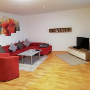 uma sala de estar com um sofá vermelho e uma mesa em Im Idyll 3 em Hengersberg
