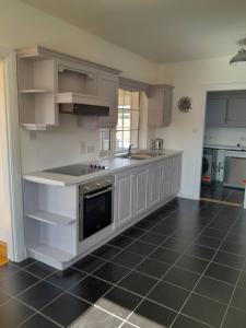 een keuken met witte kasten en een zwarte tegelvloer bij Lake Big, Five Bedroom Holiday Home Rosslare Strand, County Wexford in Mervyn