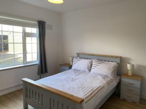 een slaapkamer met een bed met witte lakens en een raam bij Lake Big, Five Bedroom Holiday Home Rosslare Strand, County Wexford in Mervyn