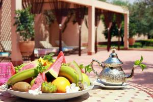 a plate of fruit on a table with a teapot at La Maison Des Oliviers in Marrakesh