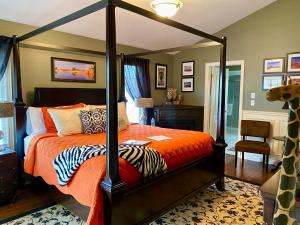 1 dormitorio con cama con dosel y sábanas de color naranja en Explorer House Bed & Breakfast en Niagara on the Lake