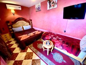 - une chambre avec un lit, un canapé et une télévision dans l'établissement Riad Fattouma Kasba, à Marrakech