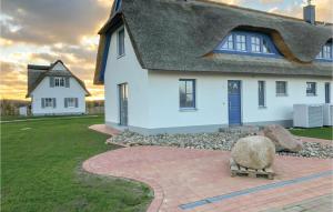 a white house with a thatched roof and a rock at Nice Home In Zierow Ot Poeler Drift in Zierow