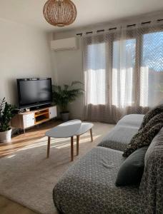 a living room with a couch and a flat screen tv at Proche du centre ville avec parking privé gratuit in Aix-en-Provence