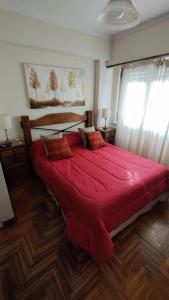 1 dormitorio con 1 cama grande de color rojo con manta roja en Departamento 2 amb ,microcentro ,con cochera en Mar del Plata