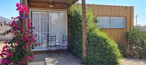 a patio with two chairs and a window and flowers at Lavanda del Valle in Vicuña