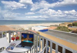 un ordenador portátil en una mesa en un balcón con vistas a la playa en Hotel Jumbo, en Rímini