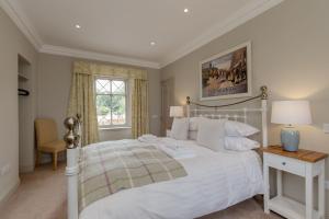 a bedroom with a white bed and a window at Home Farm Cottage in Stranraer