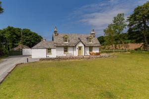 une grande maison blanche avec une grande cour dans l'établissement Home Farm Cottage, à Stranraer