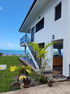 une maison blanche avec un escalier à côté de l'océan dans l'établissement Villa MATOANUI, à Tevaitoa
