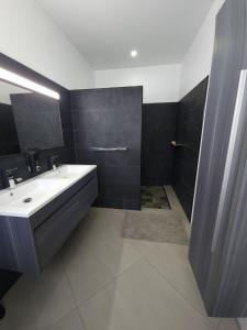 - une salle de bains en noir et blanc avec lavabo et miroir dans l'établissement Villa MATOANUI, à Tevaitoa