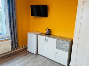 a kitchen with a refrigerator and a tv on the wall at M&M Hotel - Wilhelmsburg in Hamburg