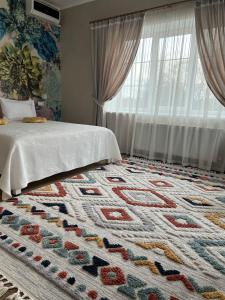 ein Schlafzimmer mit einem Bett und einem Teppich auf dem Boden in der Unterkunft Tamerlan in Chmelnyzkyj