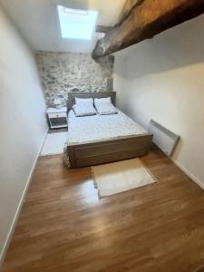 a bedroom with a bed and a wooden floor at Maison chaleureuse avec jardinet & parking gratuit in Eymet