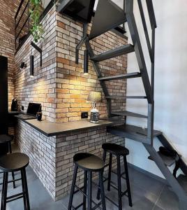 a bar with stools in front of a brick wall at Sant'Andrea - Luxury Rooms in Vucciria in Palermo