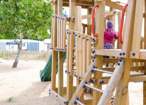 a young girl playing on a wooden playground at Dünencamping Amrum in Wittdün